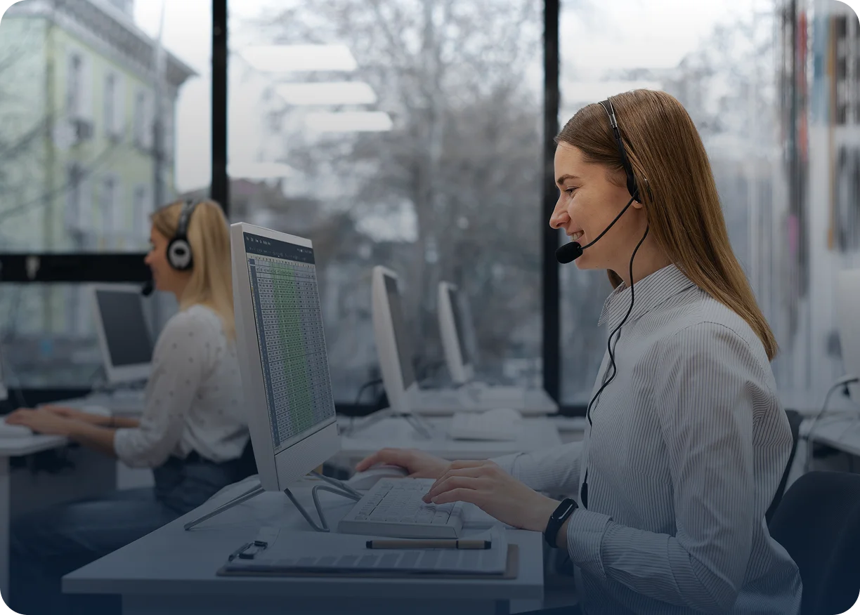 a woman wearing a headset sits at a desk focused on her work